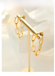 Detail of bohemian gold chain link earrings hanging on a luxury metal jewelry display