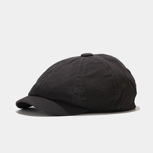 Detail view of stitching and texture on a dark grey canvas newsboy cap with top button