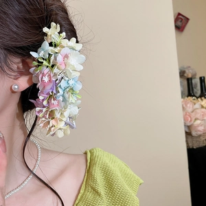 Detail of elegant pastel fabric flower hair pin worn on a side ponytail style