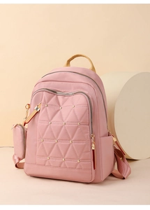 Detalle de mochila rosa de oxford con texturas acolchadas triangulares y remaches dorados