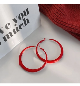 Close-up of matte red geometric hoop earrings with a modern minimalist metal design