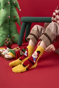 Detail of warm yellow coral fleece Christmas socks featuring a red Santa Claus pattern