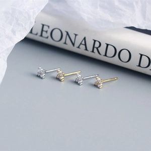 Macro detail of S925 silver and gold four-leaf flower stud earrings with sparkling crystals