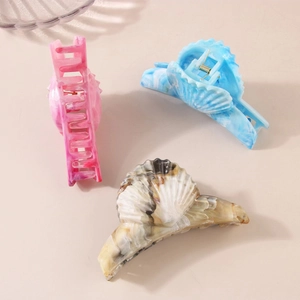 Three large shell-shaped claw clips in pink, blue, and marble beige resin finish