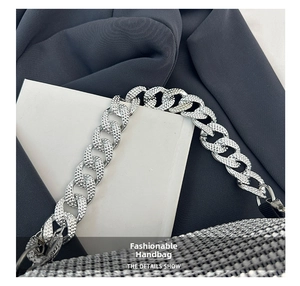 Dettaglio macro del manico a catena d'argento con strass scintillanti sulla borsa a bauletto
