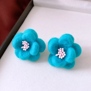Macro shot of blue wool felt flower earrings with delicate white beaded stamens detail