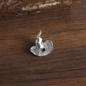 Macro shot of silver witch hat ring with black gemstone on dark wooden texture