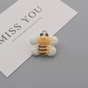 Macro shot of a yellow and white resin bee charm with a metal ring for DIY jewelry making