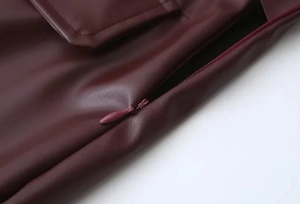 Makroaufnahme einer weinroten PU-Lederjacke mit Reißverschluss und Taschendetails