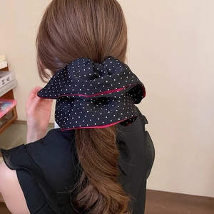 Detailed back view of a large black polka dot bow hair clip with red edge piping