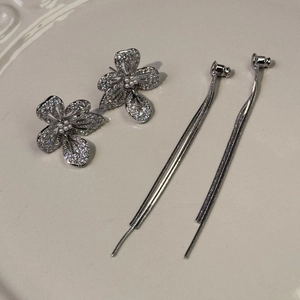 Vue détaillée de boucles d'oreilles fleur argentées avec pavé de zircons et glands