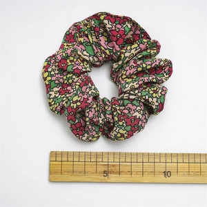 Detail of floral fabric scrunchie showing rose pattern texture and 10cm diameter size