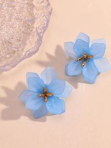 Detailed close-up of light blue floral earrings with golden centers and matte petals