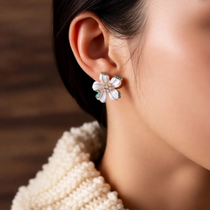 Detail of vintage flower earring with white petals and blue stones on a model