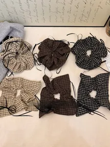 Detailed grid showing six plaid hair scrunchies with black ribbons in earth tones