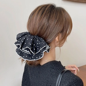 Elastico per capelli classico a pois bianchi e neri indossato su una coda di cavallo elegante