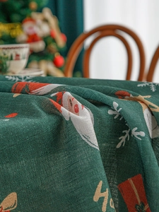 Close-up of dark green linen Christmas tablecloth with Santa and gift box patterns