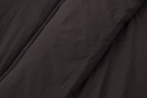 Detail of dark brown quilted water-resistant nylon fabric with thick padded texture