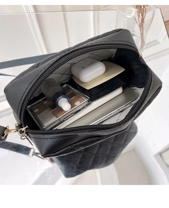Internal view of black quilted camera bag showing spacious storage for cosmetics