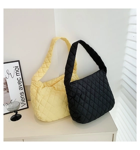 Close-up of black and yellow quilted hobo bags with padded straps on a desk