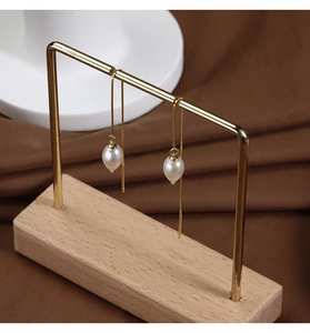 Detail view of water-drop freshwater pearl on long gold box chain on a display stand