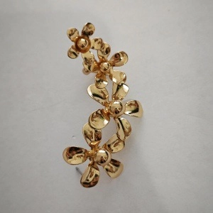 Detailopname van de gouden oormanchet met drie gepolijste metalen bloemen