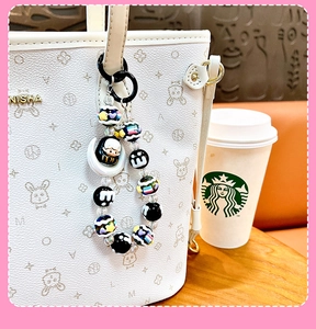 Detail of cute moon bag charm with colorful hand-painted beads on a white tote bag.
