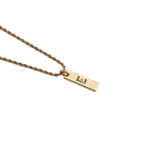 Close-up of golden necklace with rectangular pendant and colorful zircon letter E detail