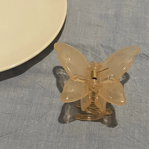 Detailed top view of a jelly amber butterfly hair claw clip on blue textured fabric