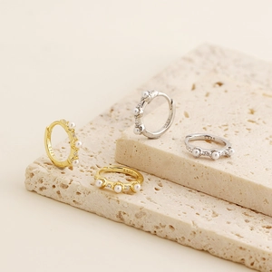 Detailed shot of S925 silver pearl and zircon hoop earrings on a natural stone base