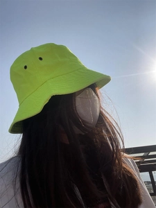 Outdoor close-up of a neon green bucket hat with high sun protection and a casual street style