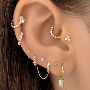 Detailed close-up of gold ear piercing charms featuring stars and moons with cubic zirconia