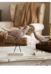 Detailopname van houten vogels set met verweerde afwerking en metalen standaards op bureau