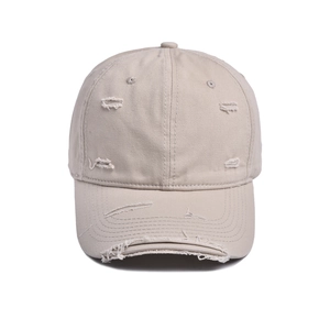 Detail shot of distressed cotton baseball cap with vintage frayed holes in beige color