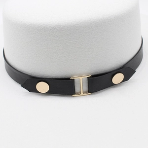 Close-up of black leather hat band featuring a gold metal buckle and round rivets detail