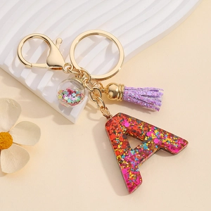 Macro detail of resin letter A keychain with colorful sequins and purple tassel
