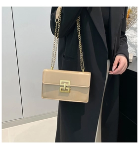 Detail of beige patent leather shoulder bag with gold chain strap and geometric buckle