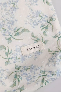 Dettaglio del tessuto floreale della borsa con pois bianchi e etichetta H&R BAG