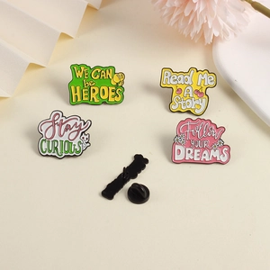 Detailed view of four colorful enamel pins featuring motivational English quotes and motifs
