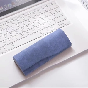 Detail of dark blue nubuck texture sunglasses case resting on a laptop keyboard