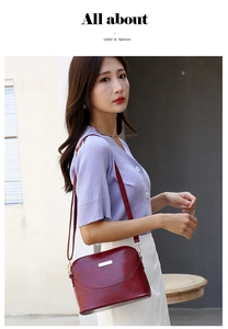 Detail view of a glossy wine red shell bag with silver hardware worn by a model