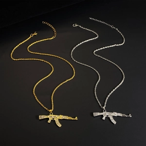 Close-up of gold and silver AK-47 rifle pendants with iced out rhinestones on black background