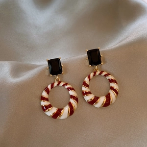 Detail of vintage gold ring earring with black gemstone and red-white enamel spiral