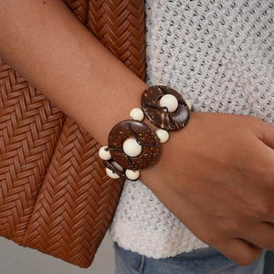 Detailed shot of ethnic coconut shell and white bead bracelet on a model's wrist