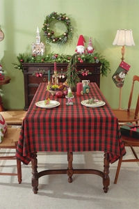 Close-up of red and green plaid Christmas tablecloth with gold lurex and fringe on wood