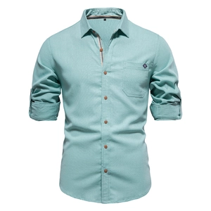 Detail of mint green cotton long sleeve shirt showing chest pocket and sleeve texture
