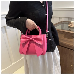 Close-up of rose red crossbody bag featuring a large bow detail and gold hardware