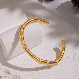 Polished 18K gold plated stainless steel open bangle with white pearls on a minimalist base