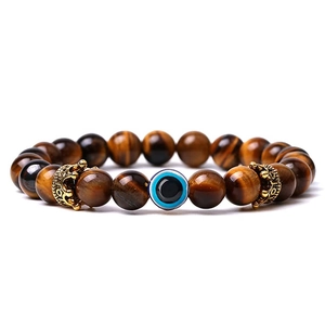 Detail of tiger eye stone beads with golden crowns and a blue evil eye charm
