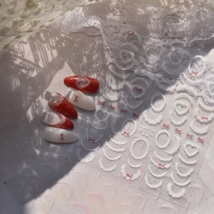 Detail of vintage white lace and heart nail stickers with elegant red press-on nails